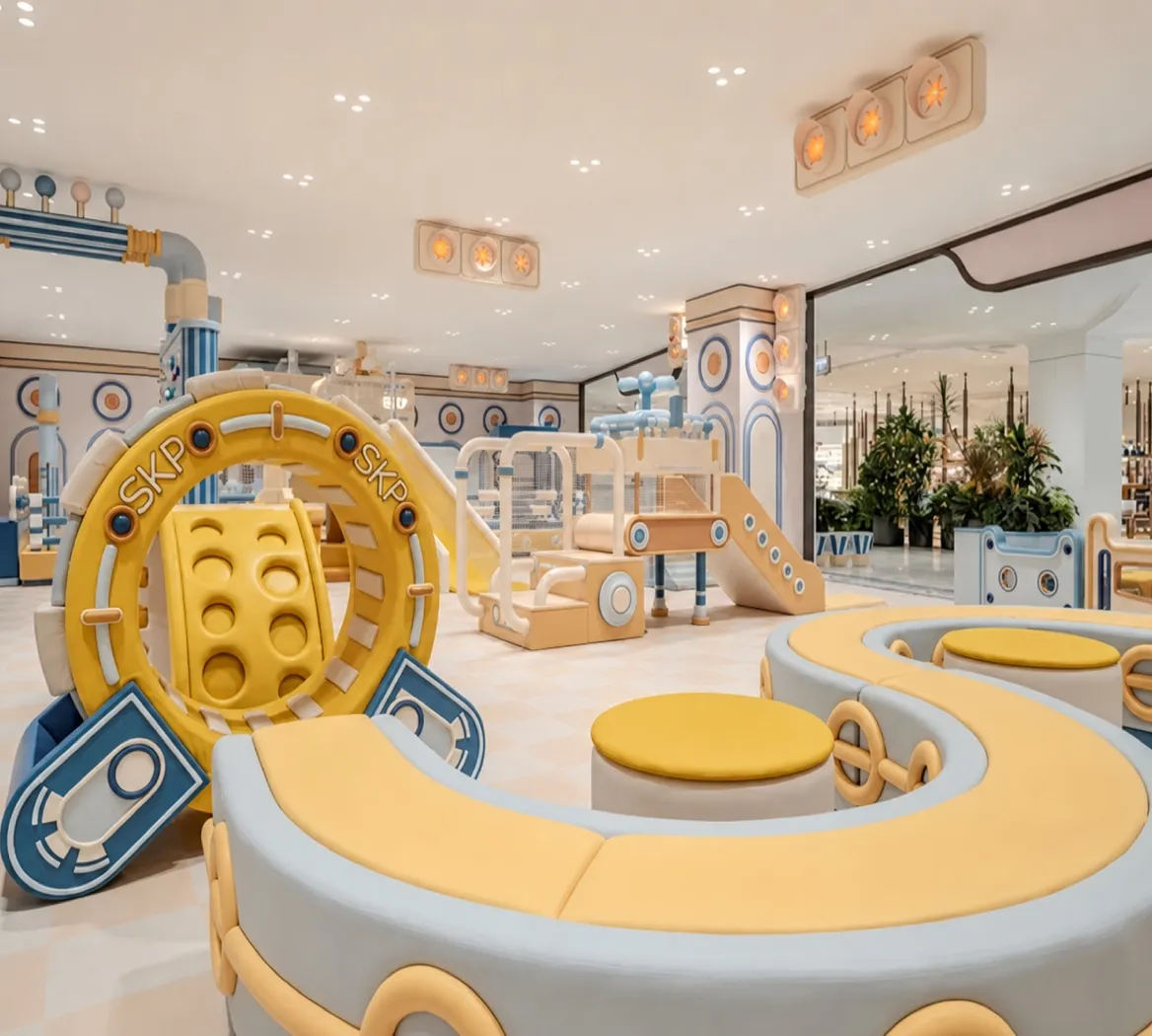 Yellow and blue indoor soft-play area with low climbing, crawling and seating elements