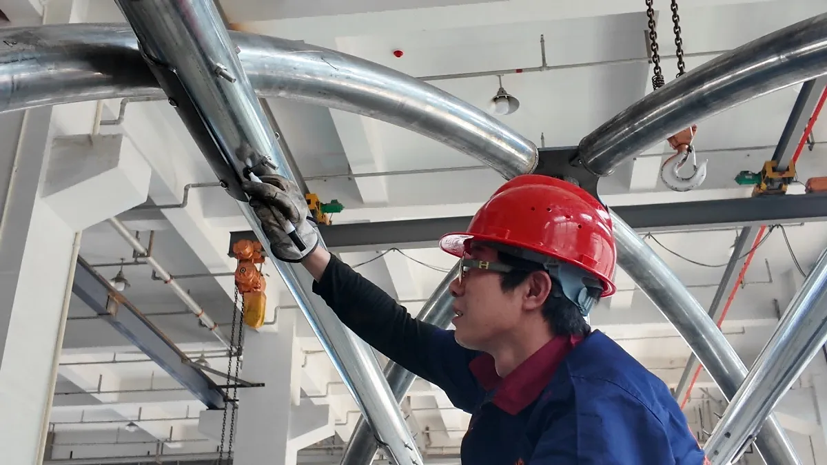 ZZRS factory worker inspecting a commercial playground steel frame before assembly